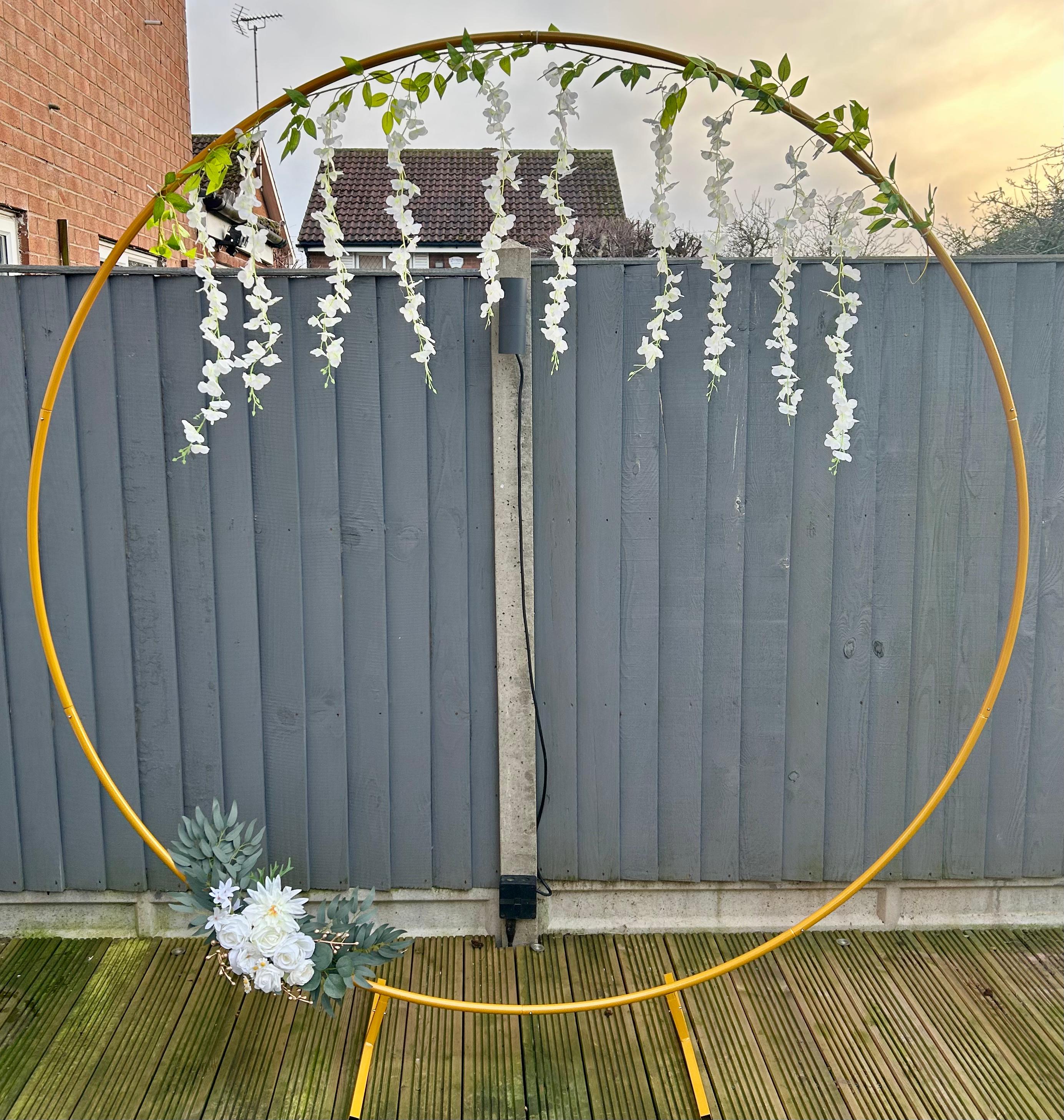 Gold moongate arch dressed with white wisteria and florals at an evening event