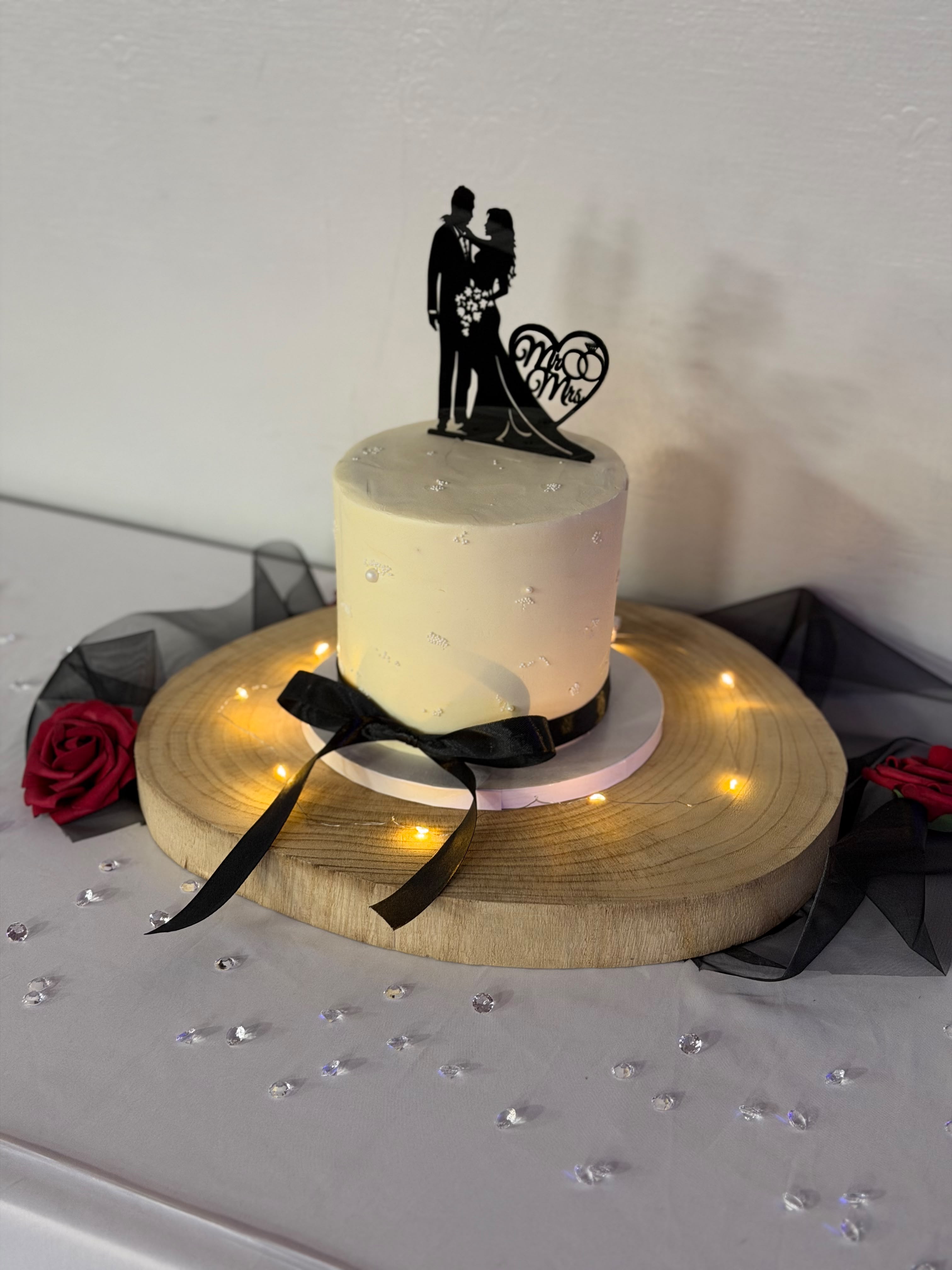 Two-tier style wedding cake with Mr and Mrs silhouette topper, fairy lights and burgundy roses
